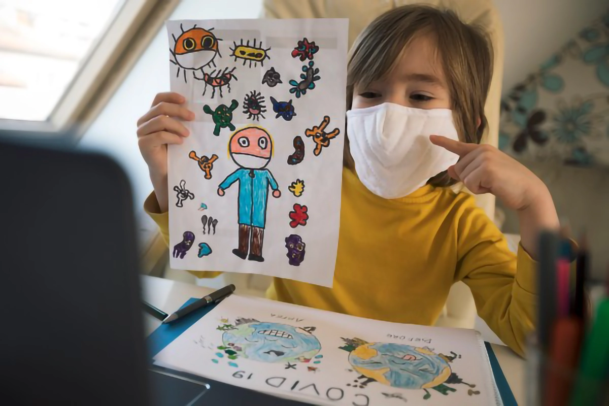 Image of a child with a face mask showing a drawing